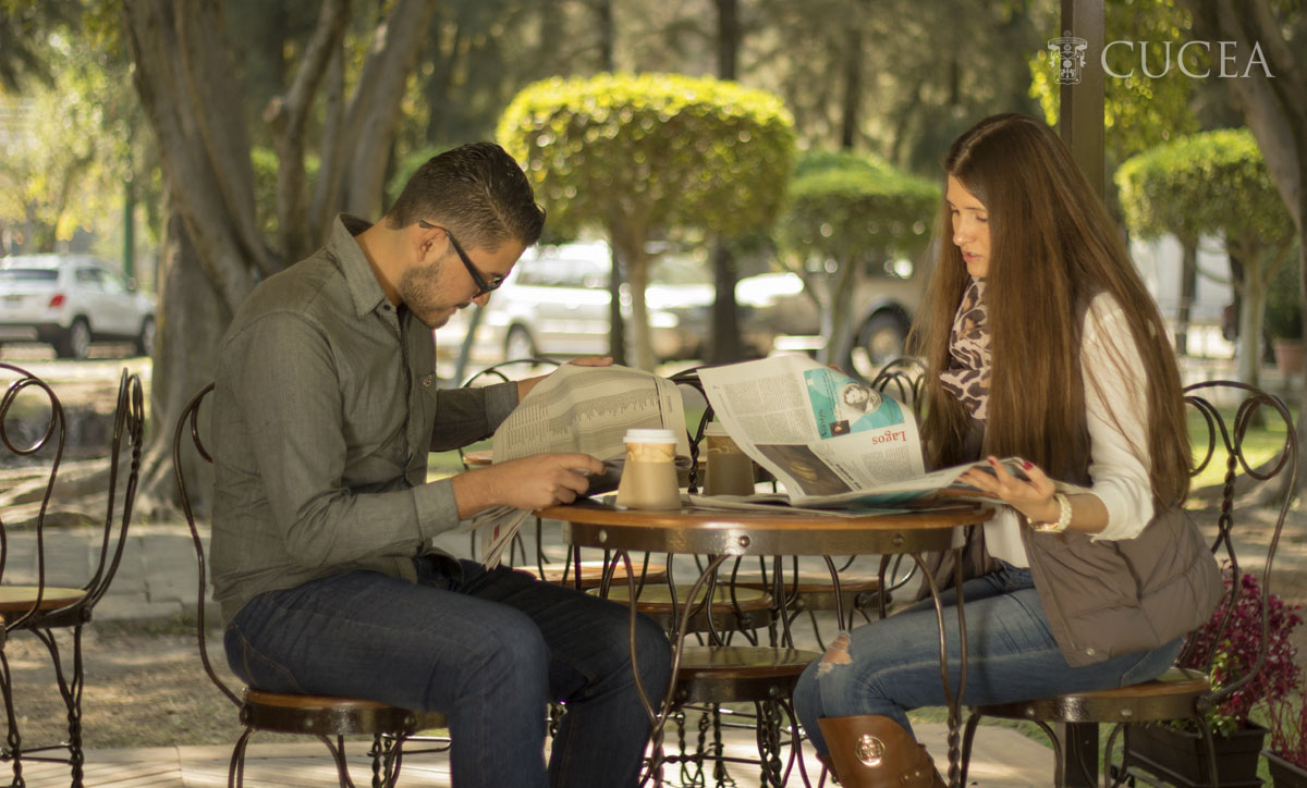 Dos estudiantes leyendo el periódico mientras toman café